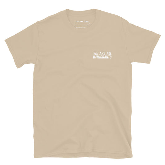 Sand t-shirt with 'We Are All Immigrants' in white text, minimalist design on chest. 